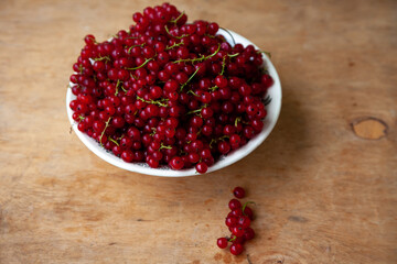 Currants in a bowl on a weeden background. Red berry. Vitamin berries. Copy space.