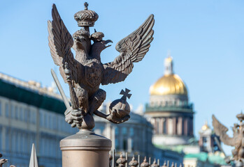 Double-headed eagle on the fence of the Alexander Column at the Winter Palace and a view of St....