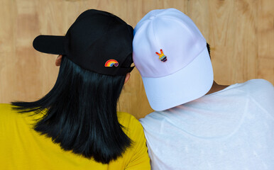 Back view LGBT women wearing baseball caps with rainbow LGBT flag symbol pins