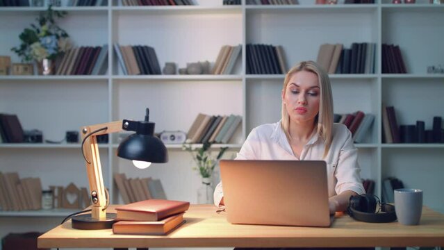 Beautiful blonde looks intently at a laptop and types