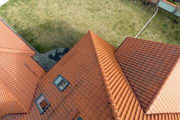 Closeup of attic windows on house roof top covered with ceramic shingles. Tiled covering of building