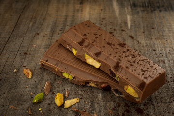 Milk chocolate with pistachios on wooden background
