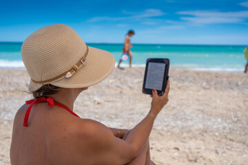 Woman reading an e-book on the beach.