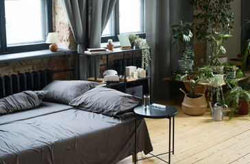Horizontal image of empty bed with house plants in background in modern bedroom