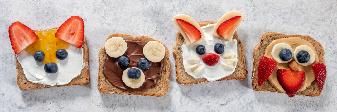 Funny animal faces toasts with spreads, butters, banana, strawberry and blueberry. Look like bunny, owl, bear, fox