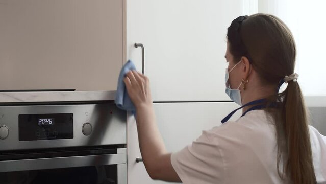 Housewife washing fridge and cooktop with detergent in the kitchen