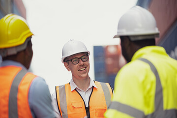 Shot of Caucasian supervisor talking with team at the container yard at the background. friendly conversations.