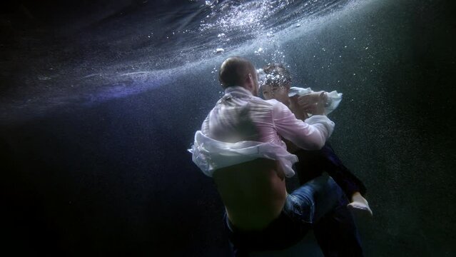 Warm feelings of a father for his son. Creative performance underwater man and his child in white shirts