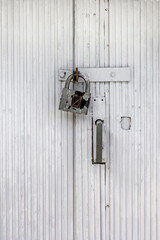 A rusty padlock hangs on an old painted wooden door