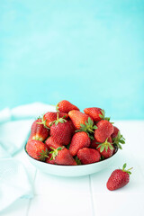 large ripe strawberries in a ceramic plate on a turquoise background