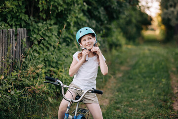 Positive smiling child girl putting on helmet for cycling