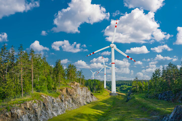 Fototapeta na wymiar Wind power generators. Wind power plant in forest. Windmills among trees. Getting energy from wind. Green energy concept. Summer Taiga with power generation facilities. Renewable energy