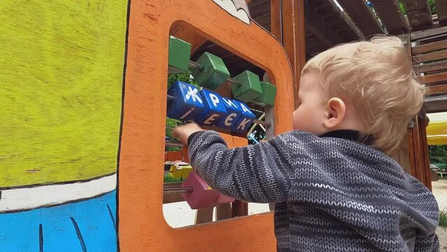 Close-up of a child's hand playing with wooden blocks on a playground in the yard. The little boy is enjoying the game. Copy space - concept of intellectual development, letters, mind, education