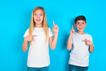 two kids boy and girl standing over blue studio background says: wow how exciting it is, has amazed...