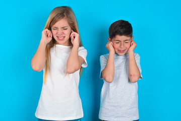 Stop making this annoying sound! Unhappy stressed out two kids boy and girl standing over blue...