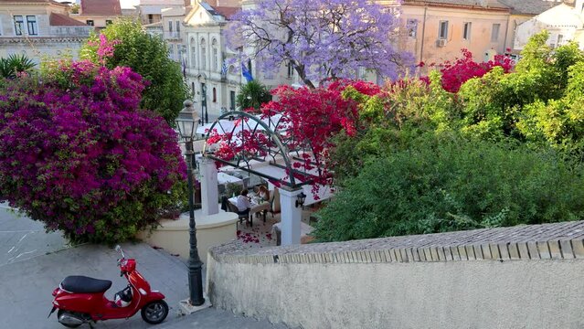 Red scooter next to Dimarchiou Square, historic part of Corfu town, Corfu Island, Greece, 4k