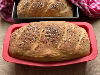Baked bread in baking dish. Homemade bread with flax and sesame seeds. Baking on a brown background.
