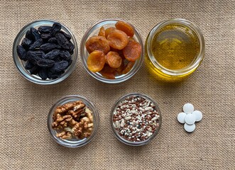 Dried fruits and vitamins on a brown background. Seeds and honey in a glass bowl. Food for a healthy diet top view.