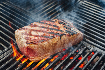 Barbecue dry aged wagyu roast beef steak grilled as close-up on a charcoal grill with fire and smoke