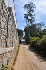 Sandy road along a high brick wall in Kodaikanal, Tamil Nadu, India