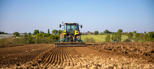 Agriculteur au volant de son tracteur labourant le champ de terre.