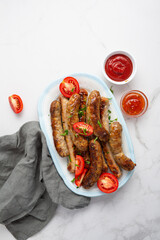 Overhead view of grilled sausages and sauces on light surface