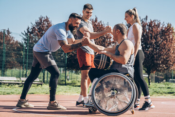 	
A physically challenged person plays street basketball with his friends.They making high five.	
