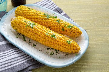 Close up of Two Sweet corn cob with butter on white plate