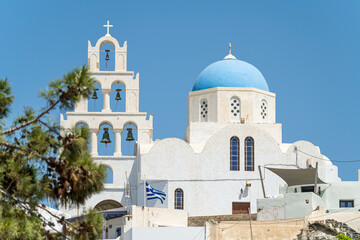 Fototapeta na wymiar Blue and white colored Greek orthodox church, bells and cross roof, during a sunny summer day