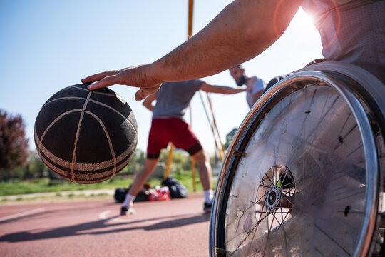 A physically challenged person play street basketball with his friends.	