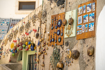 Gifts of colors typical of Santorini in Greece, bells, cats, and pendants - obrazy, fototapety, plakaty