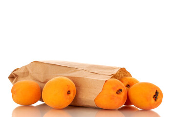 Several ripe sweet apricots with a paper bag, close-up, isolated on a white background.