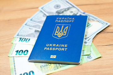 Ukrainian biometric passport id to travel the Europe with dollars and euros money on the table. Inscription in Ukrainian "Ukraine Passport". Travel or migrants concept.