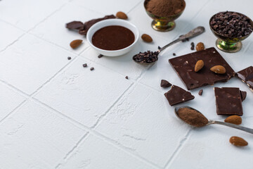 Pieces of chocolate, hot chocolate, chocolate chips and nuts on a white background