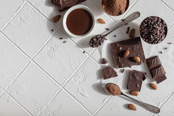 Pieces of chocolate, hot chocolate, chocolate chips and nuts on a white background