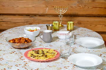 A festively laid Shabbat table with candles and a menorah.
