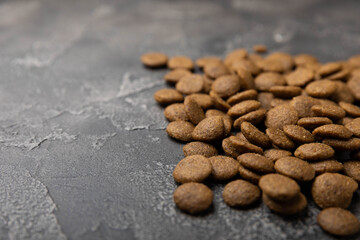 Dry dog food on a cement background. Vitamins and nutrients for good health and energy in pets. Copy space.