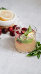 lemonade in glass on light gray concrete background. fresh summer pink drink with lemon, cherry and mint. copy space