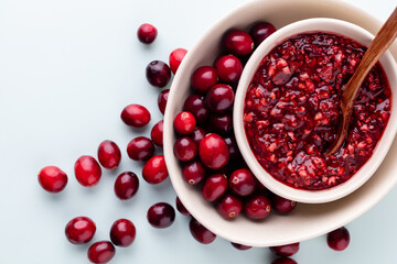 Cranberries in white bowl on pastel background.