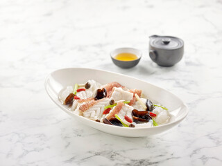 Poached Garoupa Fillet in Ginger Wine Fish Broth served in a dish side view on grey background