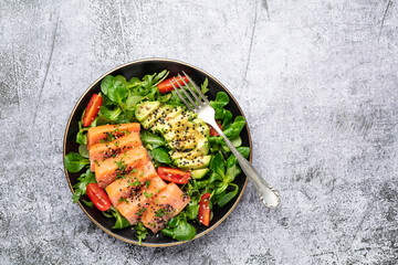 Salmon fish fillet with fresh salad, avocado top view.