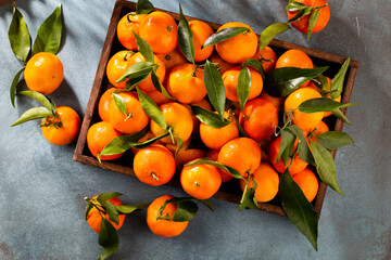 Fresh mandarin oranges fruit or tangerines with leaves in wooden box, top view - 509457647