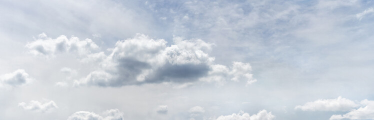 Big white curly clouds in the gray-blue sky in soft pastel colors