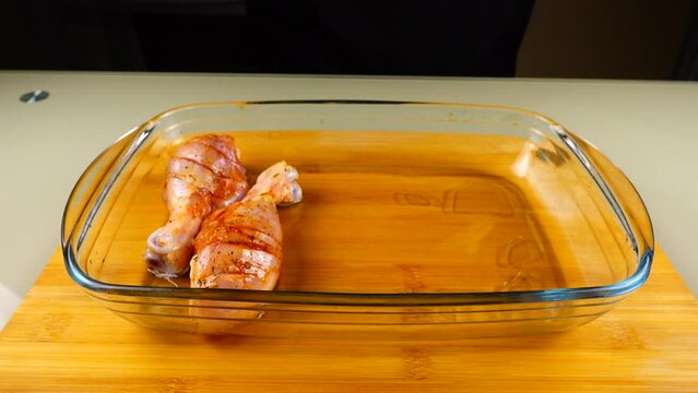 The marinated chicken legs are laid out in a glass