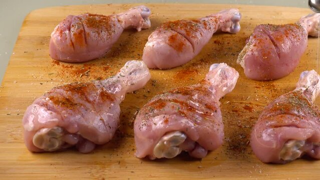 Chicken legs are sprinkled with olive oil on a cutting