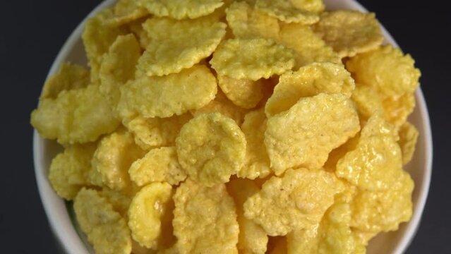 Crispy corn flakes rotating in bowl close up, dry healthy