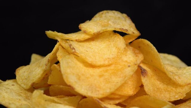 Craft crispy potato chips rotating on black background