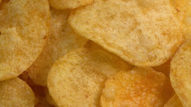 Crispy potato chips rotating in macro. Golden fried