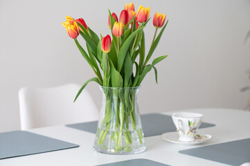 Colorful fresh tulips in glass vase on a table at home