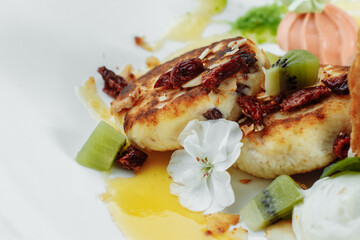 An ideal breakfast. Cottage cheese pancakes with caramel, almonds and cream sauce in a white plate. Ukrainian syrniki